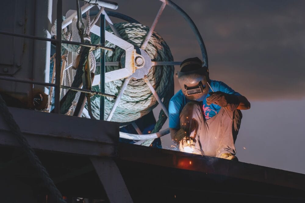 Welder using arc Welding machine to Repairing stern metal floor on deck of fishing boat at Night